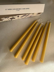 Busy Bees Hand Dipped 12 Inch Taper Candles arranged beside branded packaging on a soft neutral surface.
