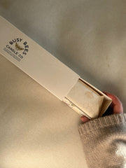Close up of Busy Bees Hand Dipped 12 Inch Taper Candles partially removed from branded packaging with soft natural lighting.