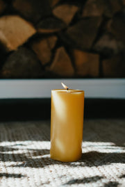 Yellow Busy Bee candle on a textured surface with a stone wall background