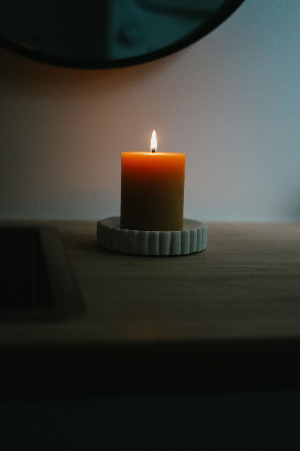 Busy Bees 3 Inch by 3.5 Inch pillar candle burning on a ceramic tray in a softly lit room.