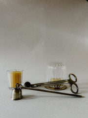 Busy Bees Candle Snuffer and Wick Trimmer set styled beside a glass candle holder on a minimal neutral surface.