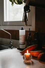 Busy Bees Votive Candles 4 Pack styled beside a bathtub with warm candlelight and fresh flowers in a cozy bathroom setting.