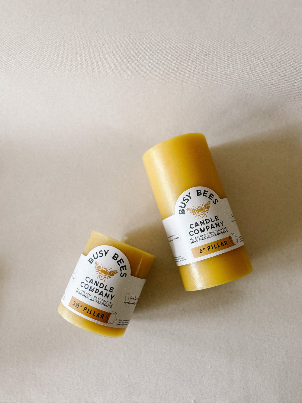 Two yellow candles from Busy Bees Candle Company on a beige background
