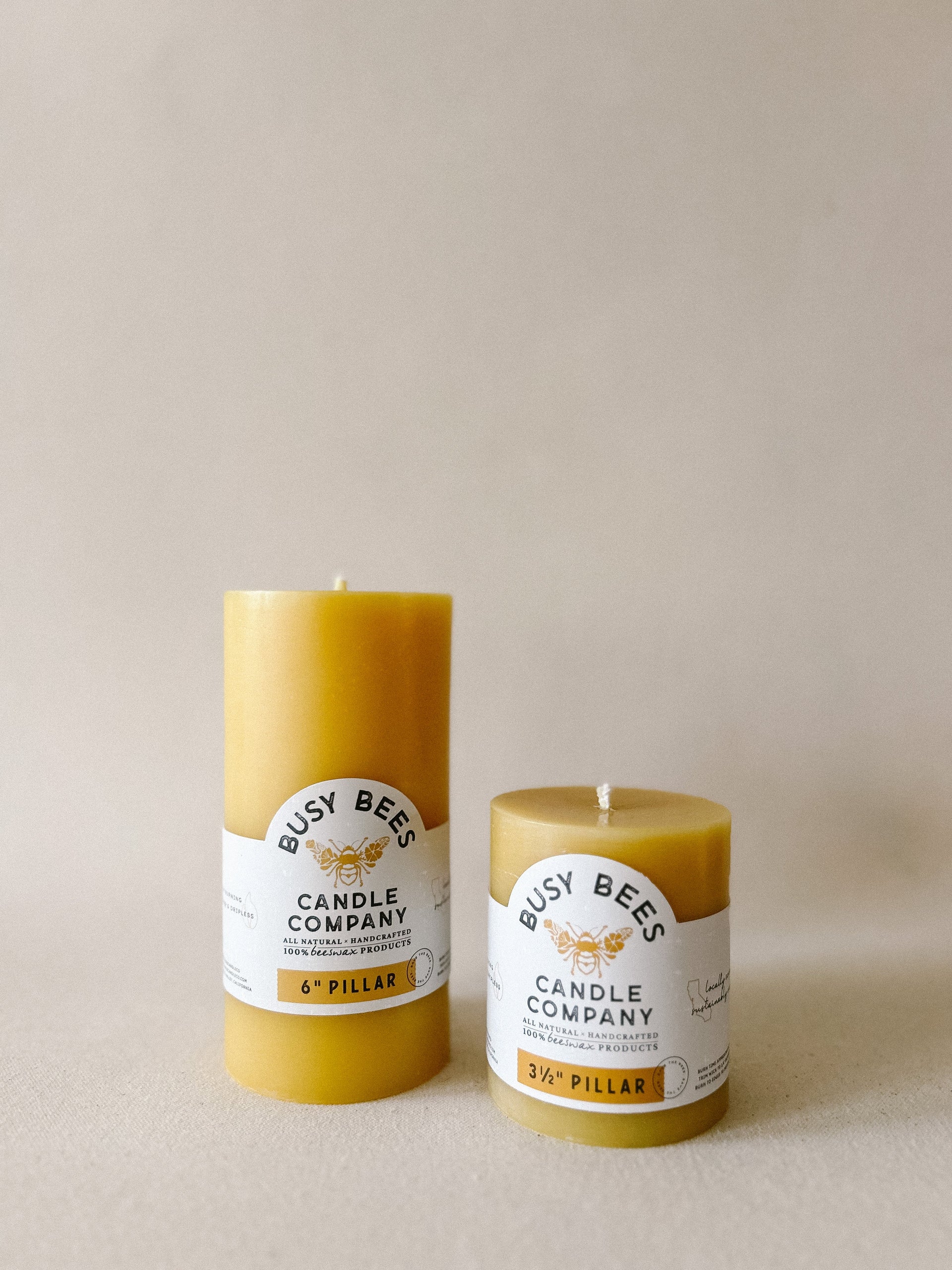 Two yellow candles from Busy Bees Candle Company on a beige background