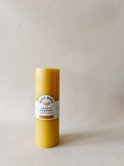 Busy Bees 3 Inch Pillar Trio beeswax candle with branded label displayed in soft natural lighting.