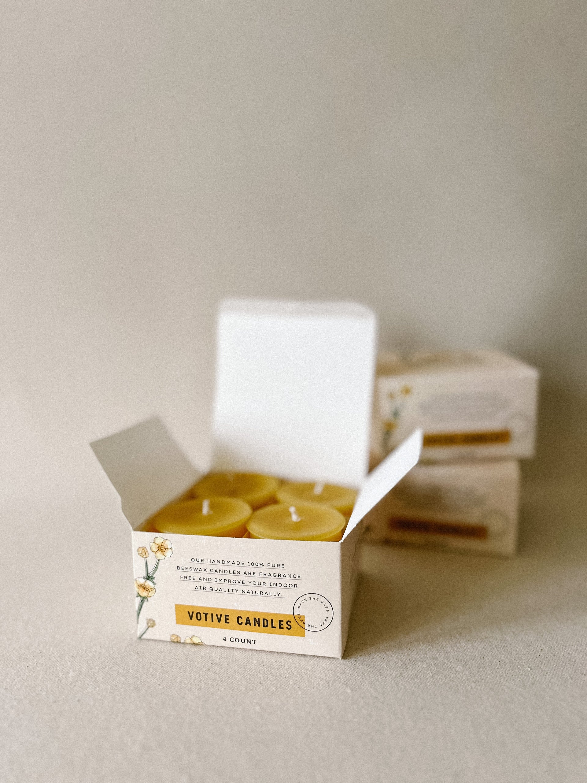 Busy Bees Votive Candles 4 Pack displayed with open branded packaging on a minimal neutral background.