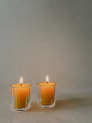 Two Busy Bees Ribbed Glass Tea Light Holders with lit candles displayed against a soft neutral background.