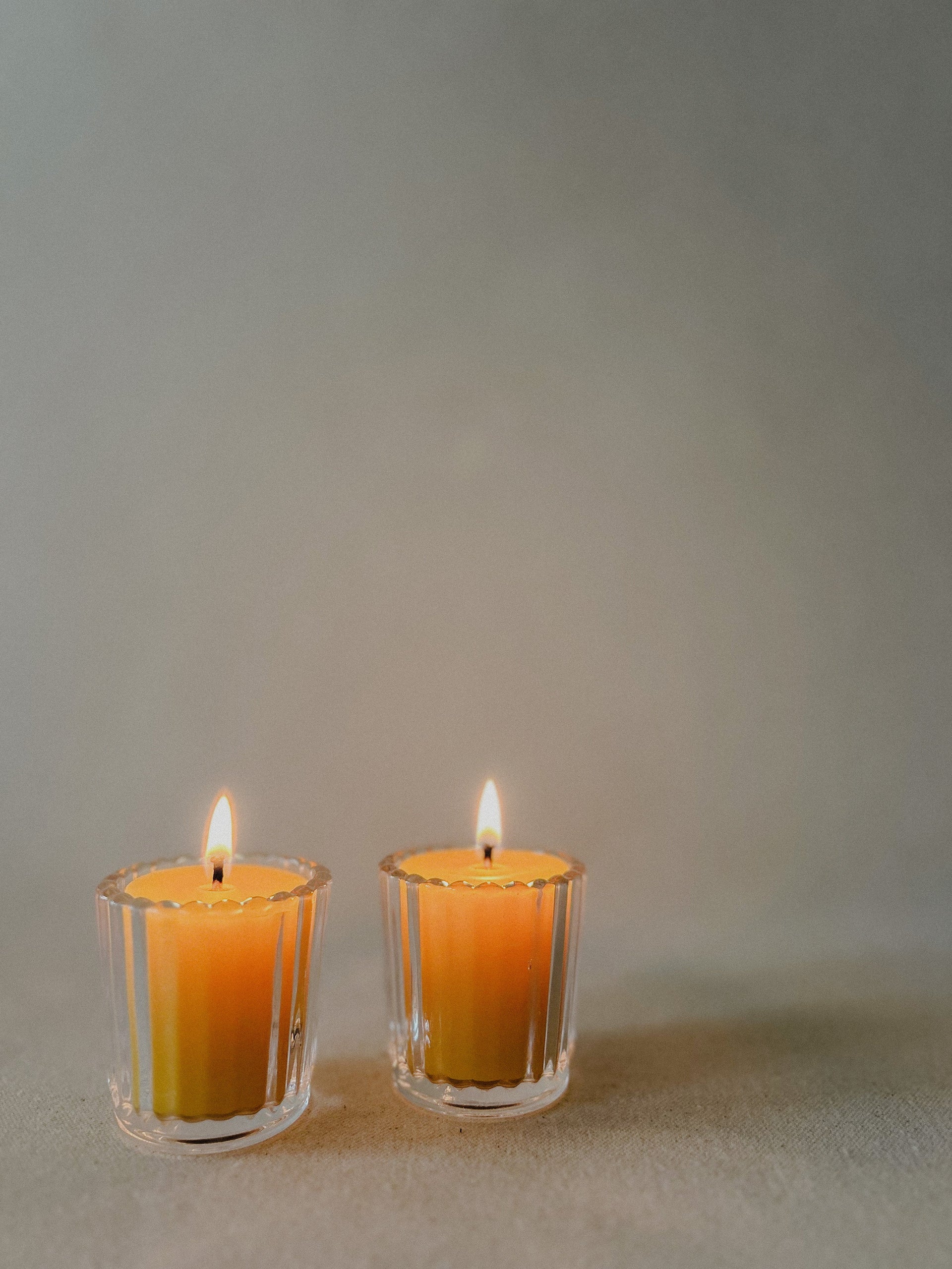 Two Busy Bees Ribbed Glass Tea Light Holders with lit candles displayed against a soft neutral background.