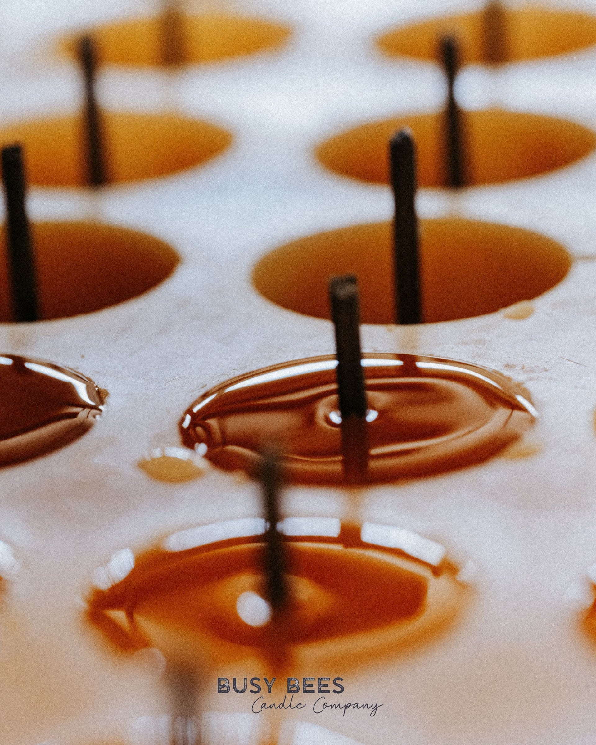Close up of multiple lit Busy Bees Bulk Loose Tea Light Candles with melted wax glowing in warm light.