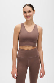 Woman wearing an Elastique Athletics brown athletic outfit on a white background