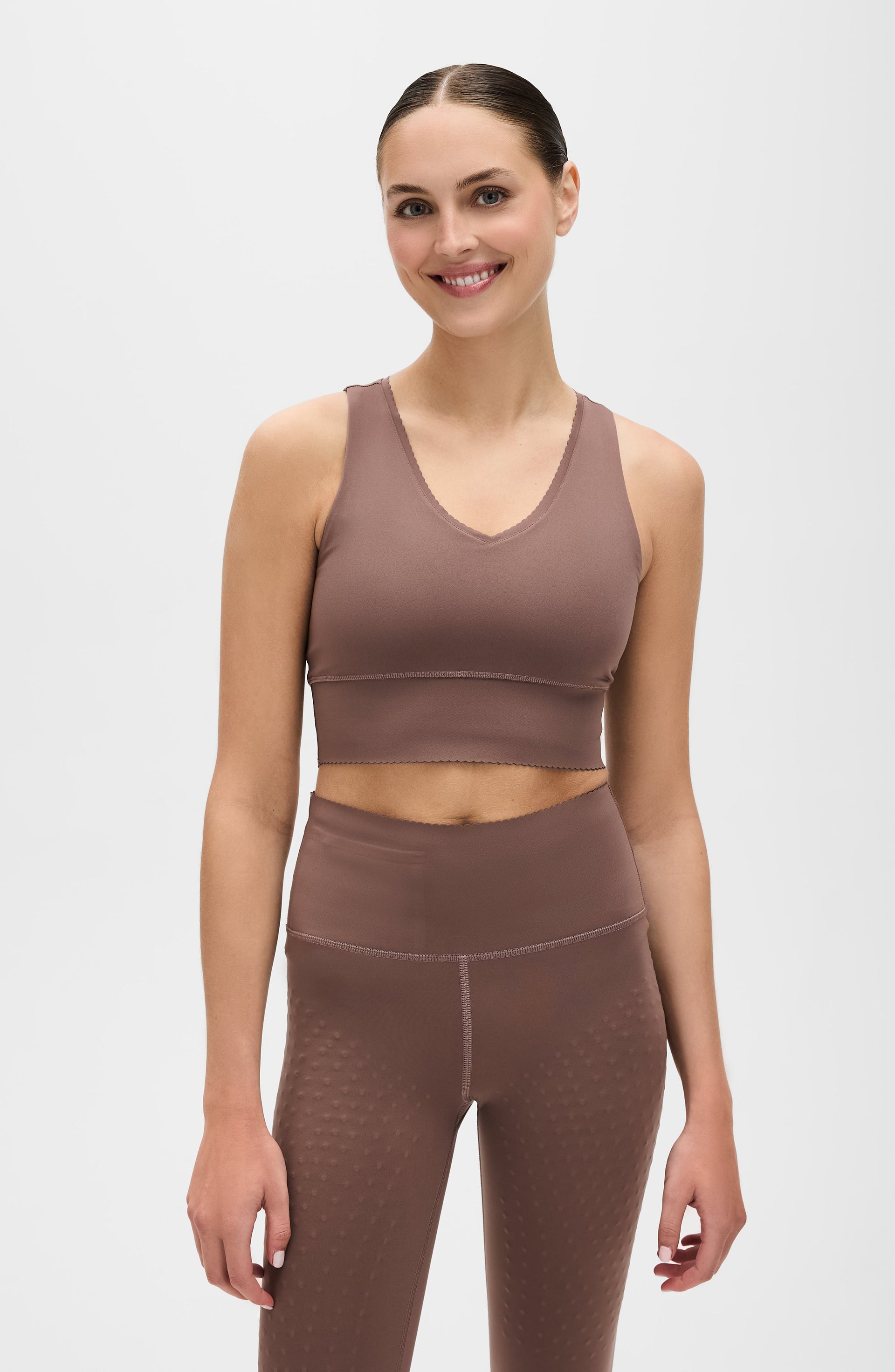 Woman wearing an Elastique Athletics brown athletic outfit on a white background