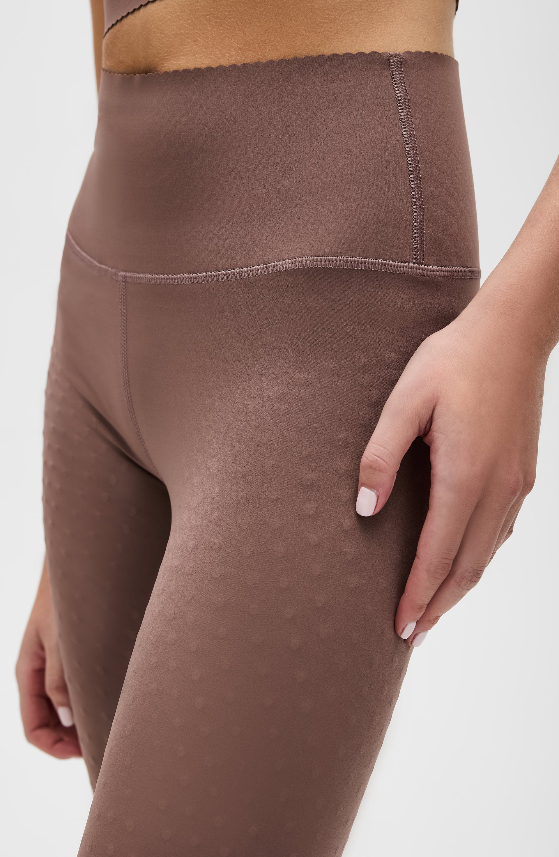 Close up detail of the Elastique Athletics Adorn Leggings in taupe featuring the high waisted fit and textured fabric pattern along the thigh.