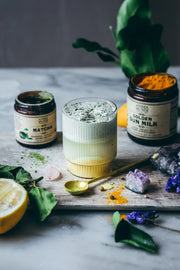 Creamy matcha latte prepared with Anima Mundi Matcha and Golden Sun Milk beside crystals, citrus, and botanical ingredients.
