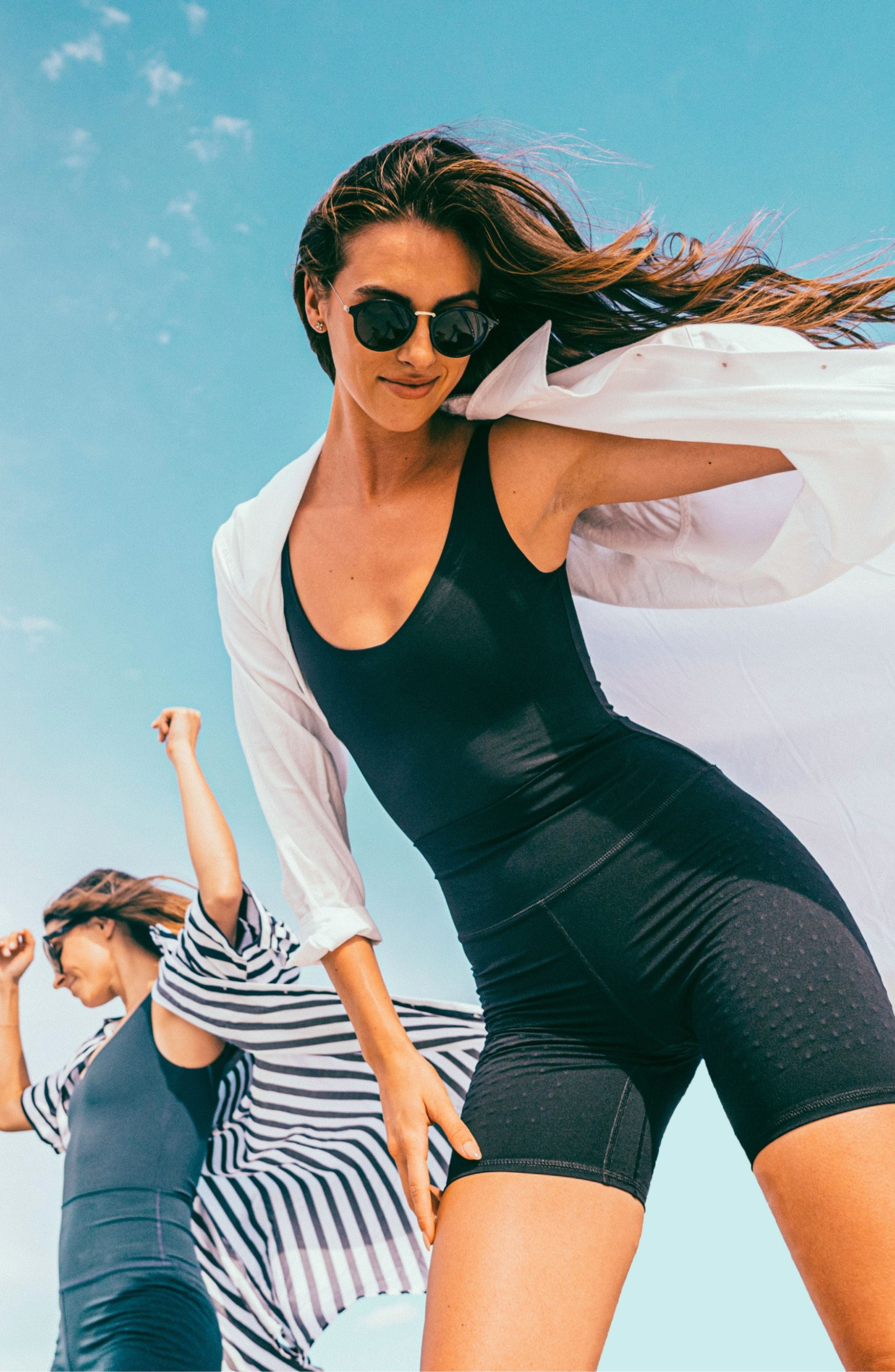 Woman posing outdoors in the Elastique Athletics L'Original Lymphatic Bike Short in dark green with a matching sleeveless top and sunglasses.