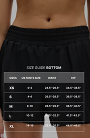 Size guide graphic for the Elastique Athletics L'Original Flowy Short with measurement overlay text across a close up image of the black shorts.