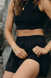 Close up waistband detail of the Elastique Athletics L'Original Flowy Short in black paired with a matching crop top.