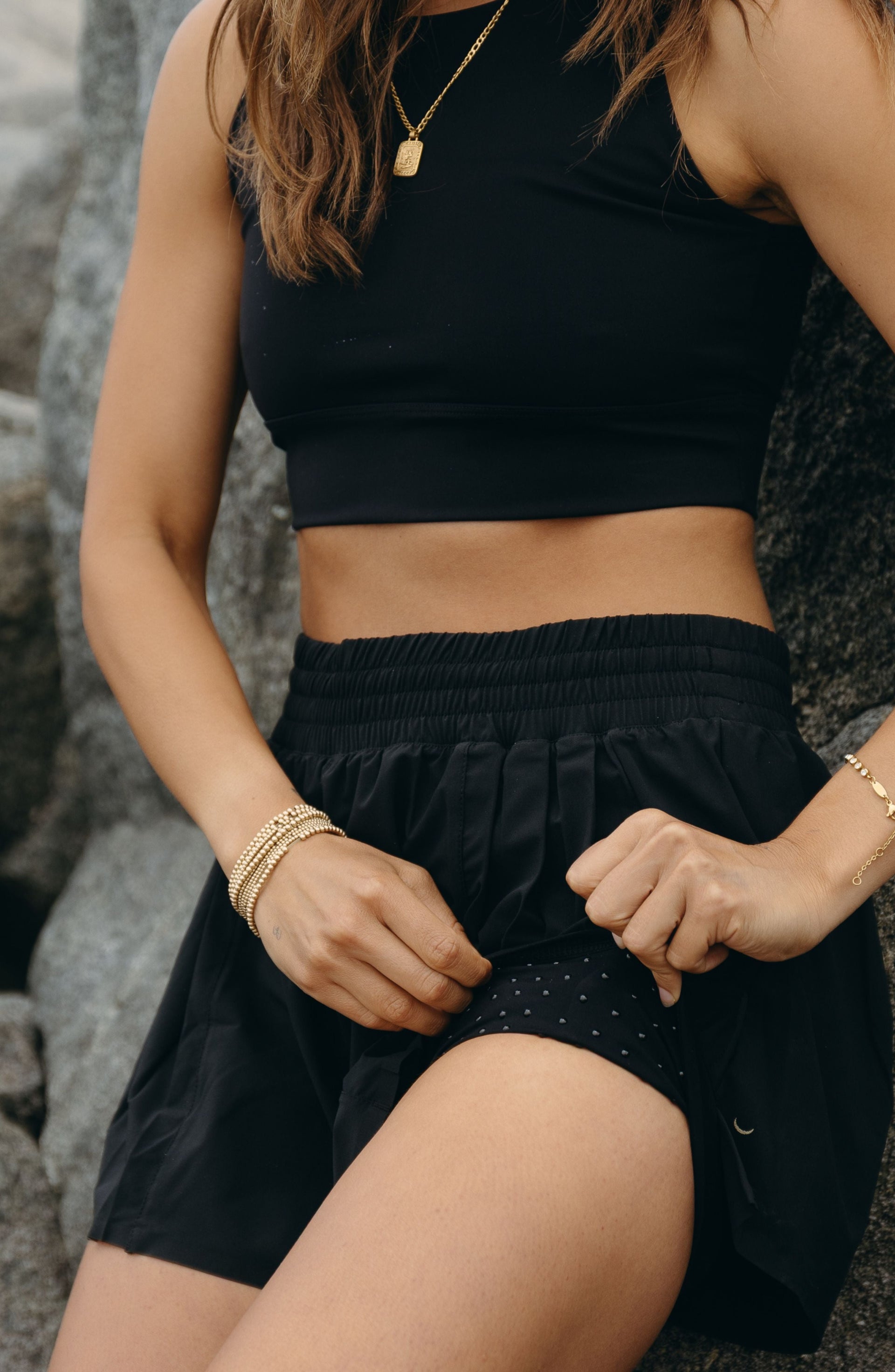 Close up waistband detail of the Elastique Athletics L'Original Flowy Short in black paired with a matching crop top.