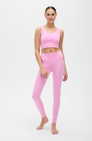 Full body studio portrait of a woman wearing the Elastique Athletics Rise Leggings Vie en Rose in soft pink with a matching sports bra.