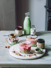 Rose matcha lattes prepared with ceremonial matcha and botanical ingredients on a marble serving board.