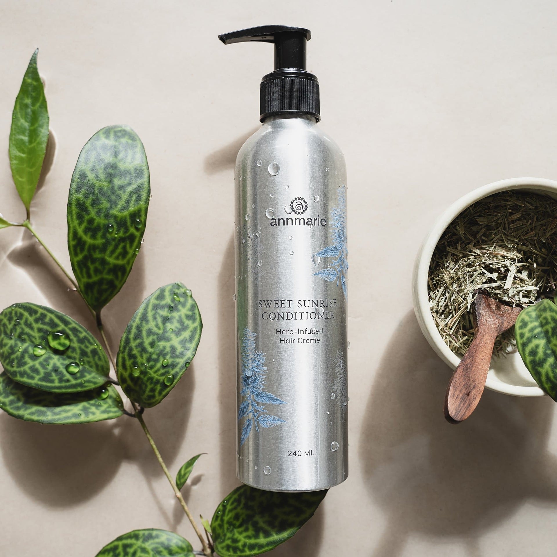 Sweet Sunrise Conditioner bottle surrounded by green leaves and botanical ingredients