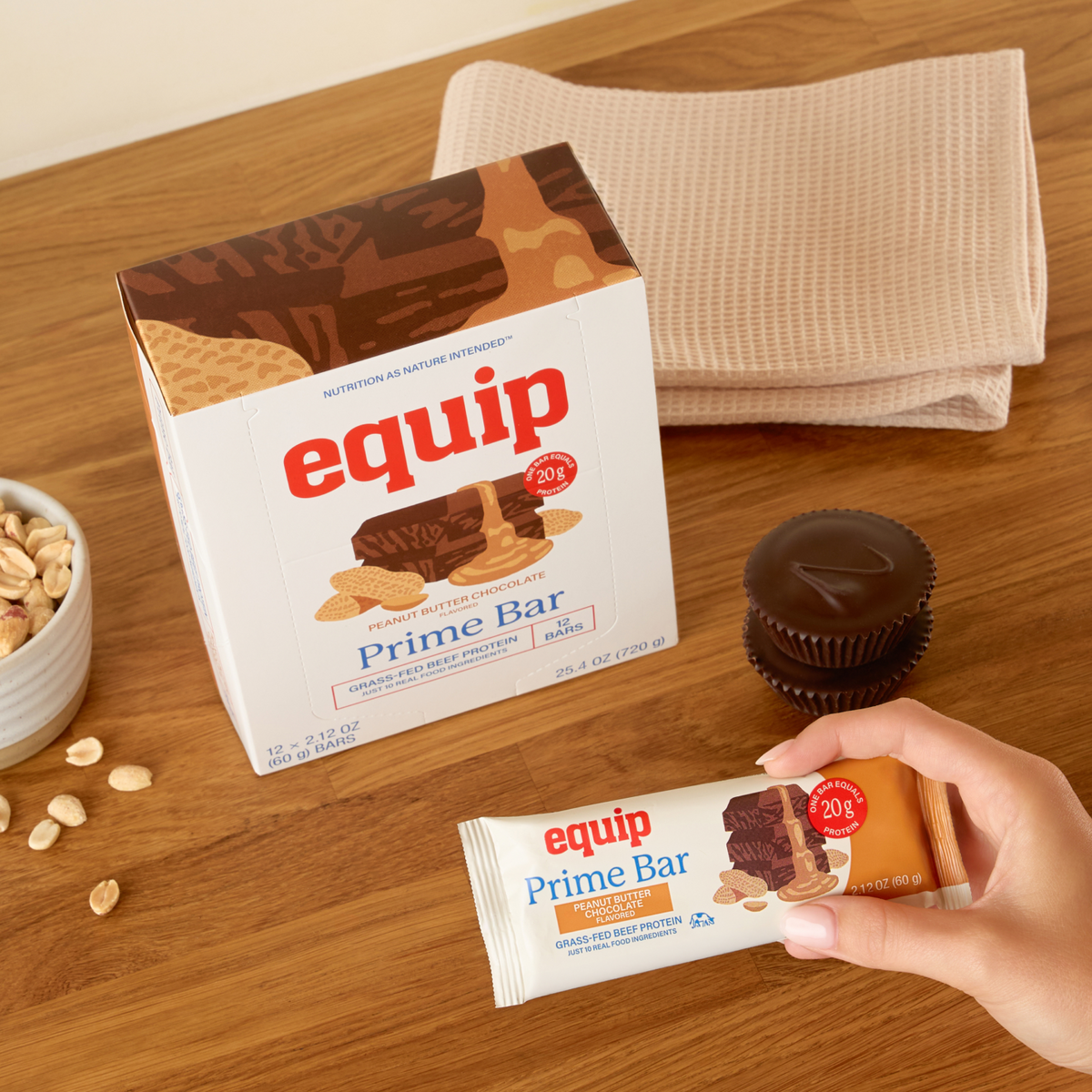 Equip Prime Bar peanut butter chocolate package with an unwrapped bar on a wooden surface