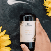 Annmarie Radiant Skin Silk Body Lotion displayed with botanical elements and sunflower accents