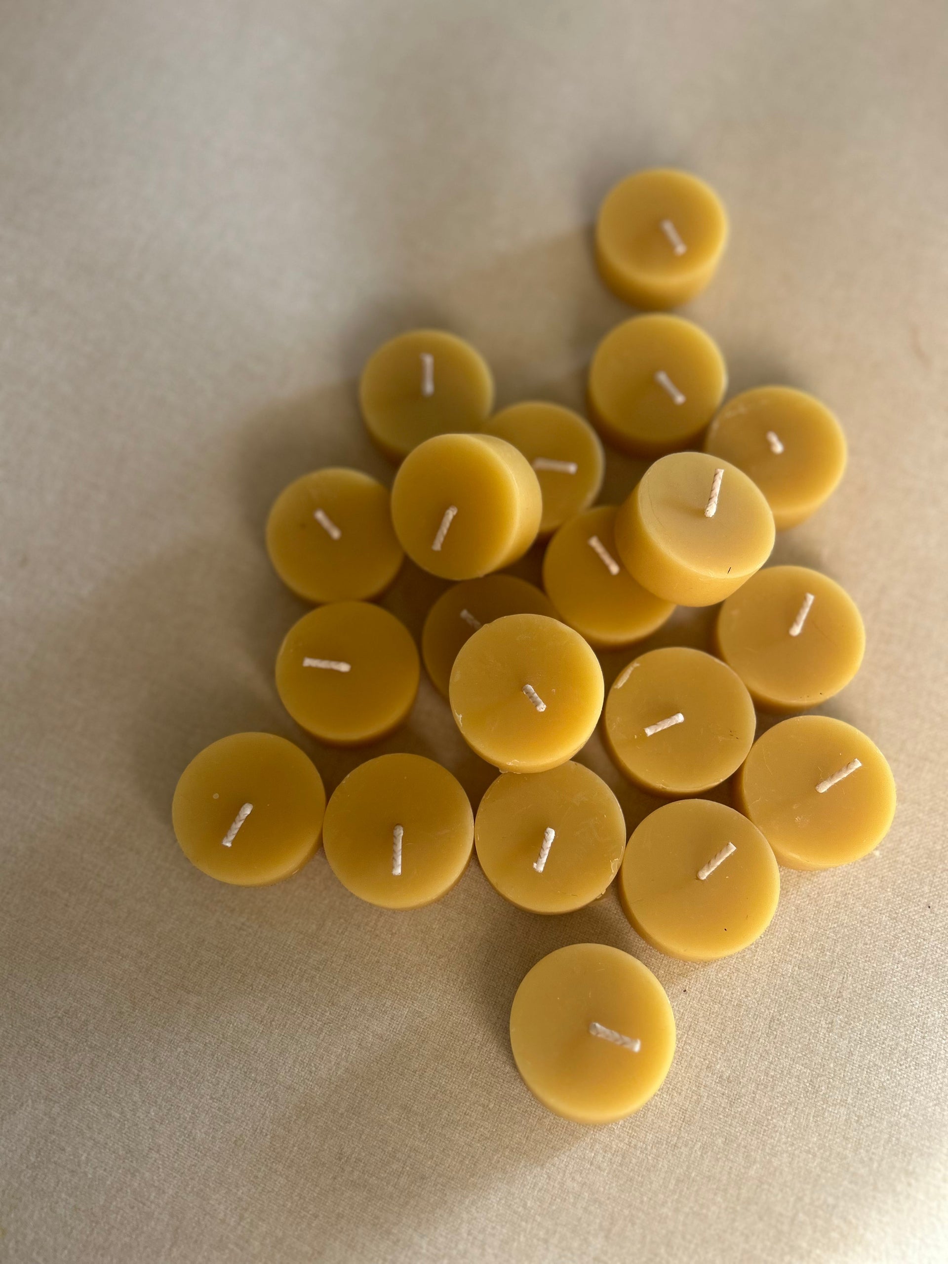 Busy Bees Bulk Loose Tea Light Candles arranged in a clustered flat lay on soft neutral fabric.