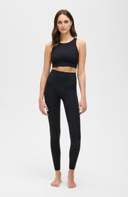 Full body studio portrait of a woman wearing the Elastique Athletics The Fierce Leggings in black with a matching sleeveless crop top.