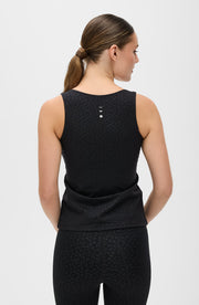 Back view of a woman wearing the Elastique Athletics The Fierce Tank in black with a racerback silhouette and matching leggings.