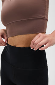 Close up waistband detail of the Elastique Athletics Adorn Leggings in black paired with a taupe sports bra.