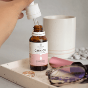 Neurogan Health GHK-Cu serum bottle with dropper beside skincare accessories.