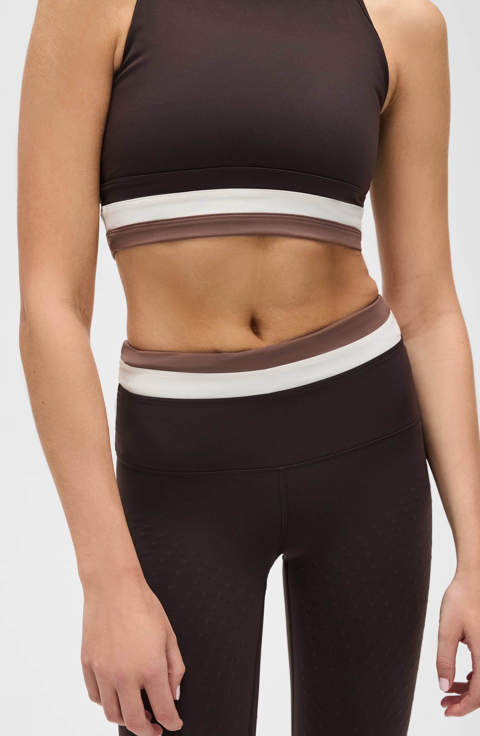 Close up detail of the Elastique Athletics Le Monde black crop top and leggings highlighting the white waistband trim and sculpted fit.