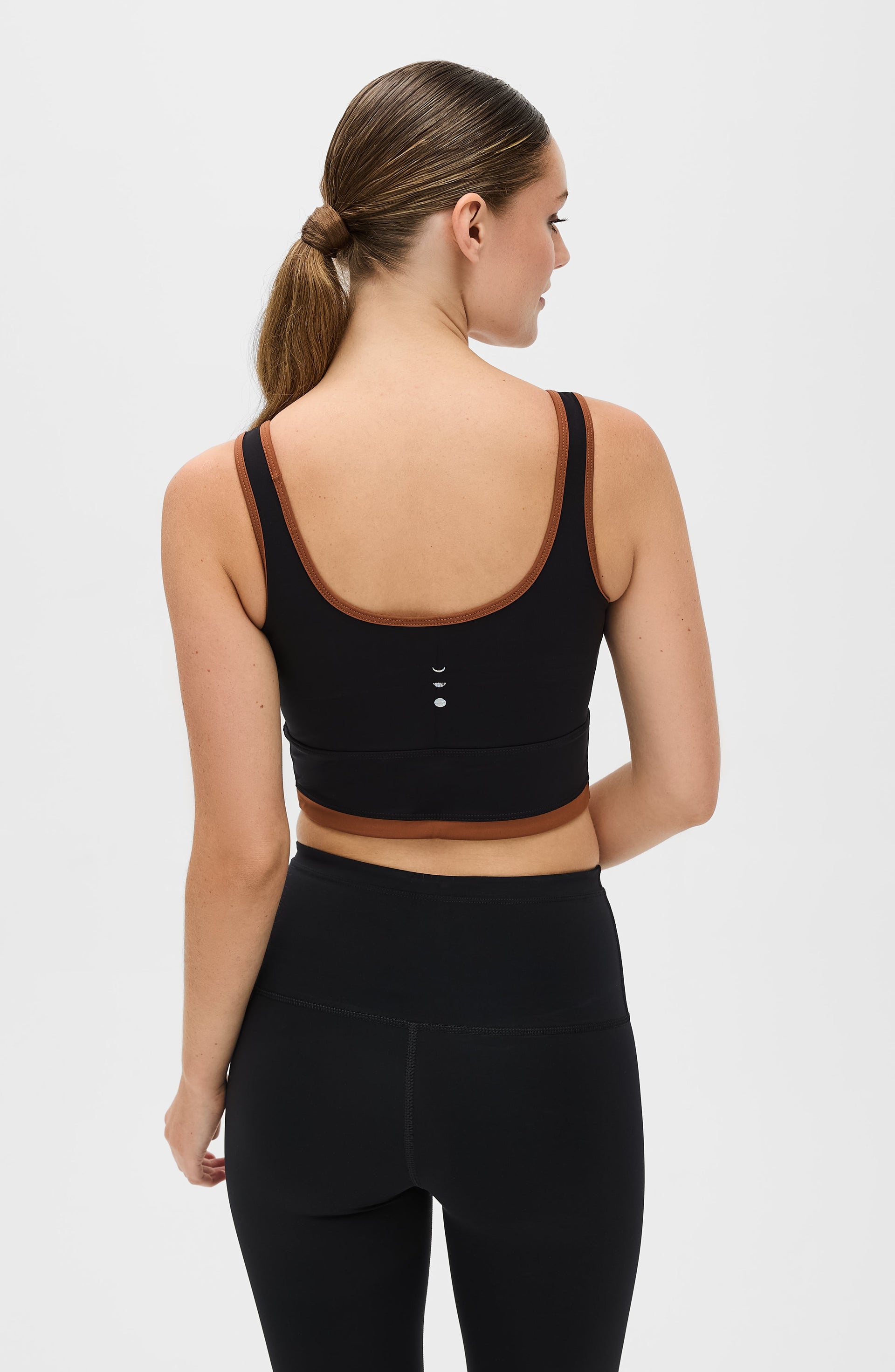 Back view of a woman wearing the Elastique Athletics Lisse Bra in black with matching biker shorts.