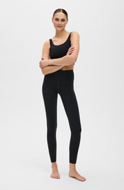 Woman wearing Elastique Athletics Lisse black athletic leggings and sports bra on a white background