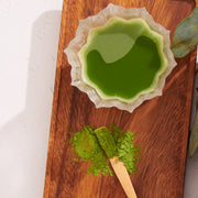 Magic Hour green matcha powder in a small bowl on a wooden board with a wooden spoon.