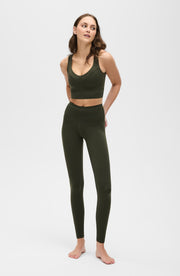 Full body studio portrait of a woman wearing the Elastique Athletics Le Divine Lymphatic Bra in olive green with matching high waisted leggings.
