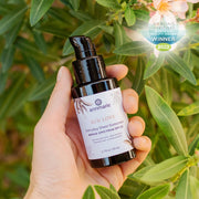 Annmarie Sun Love Everyday Sheer Sunscreen held outdoors among lush greenery