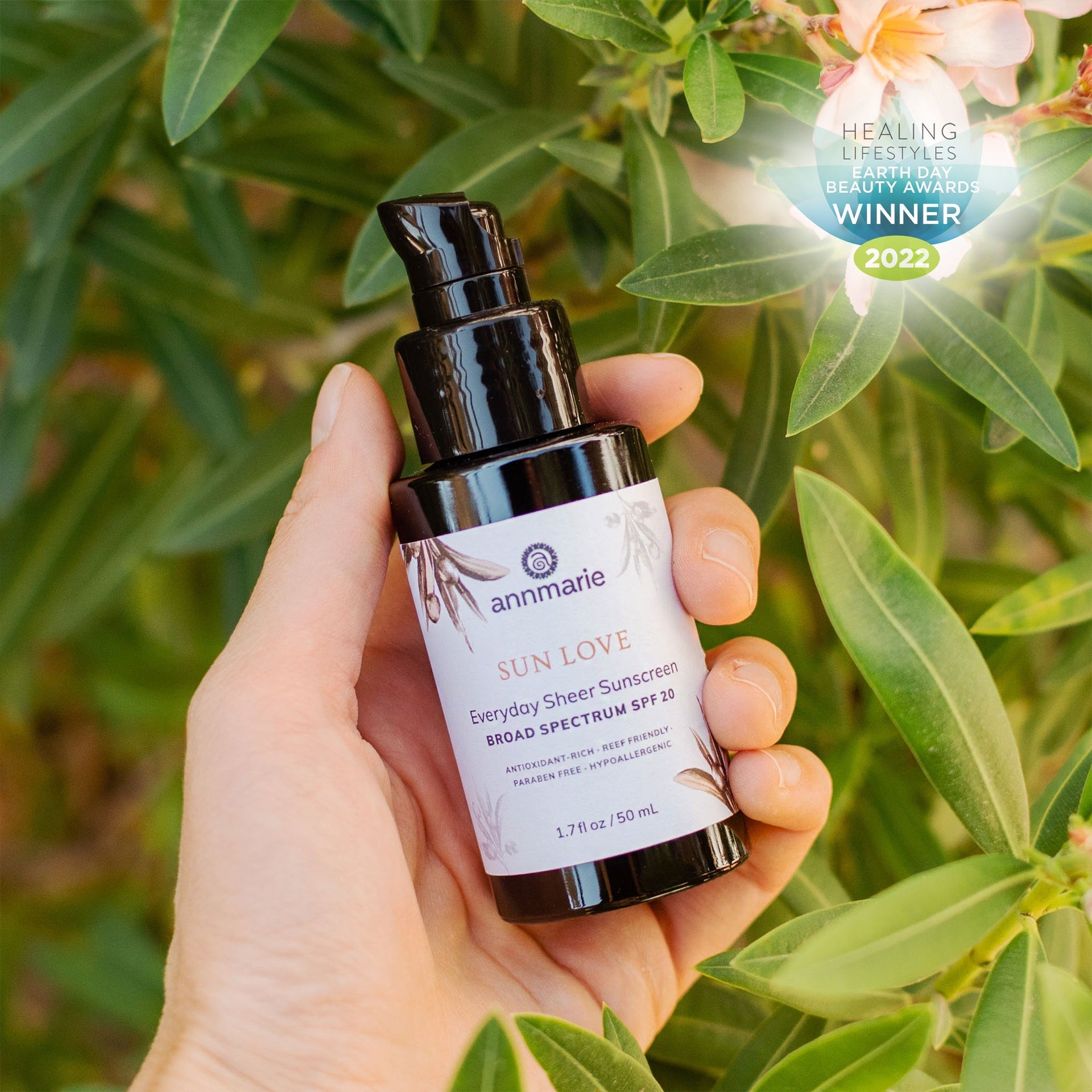 Annmarie Sun Love Everyday Sheer Sunscreen held outdoors among lush greenery
