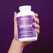 Hand holding Paleovalley Grass Fed Organ Complex, a grass fed organ supplement made with freeze-dried beef liver, heart, and kidney.