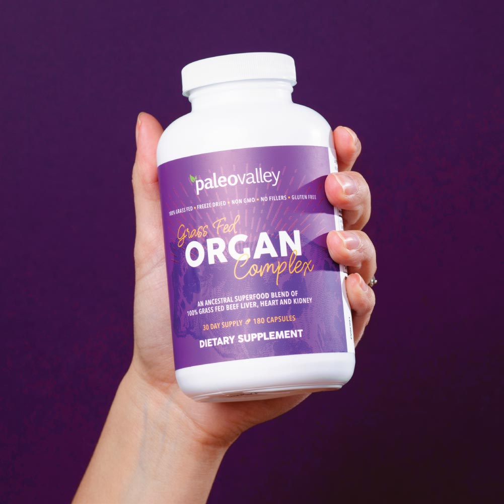 Hand holding Paleovalley Grass Fed Organ Complex, a grass fed organ supplement made with freeze-dried beef liver, heart, and kidney.
