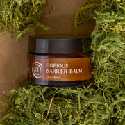 Code of Harmony Copious Barrier Balm jar styled with green moss