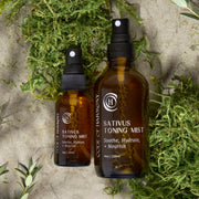Code of Harmony Sativus Toning Mist 1 oz and 4 oz bottles styled with green moss