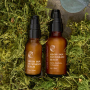 Code of Harmony Virgin Skin Antioxidant Serum 0.5 oz and 1 oz bottles nestled in green moss
