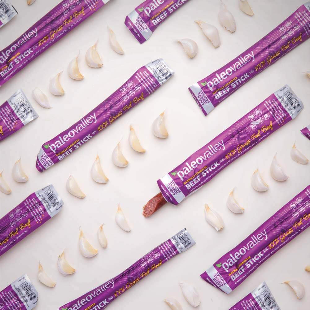 PaleoValley garlic summer sausage beef sticks with fresh garlic cloves on white background