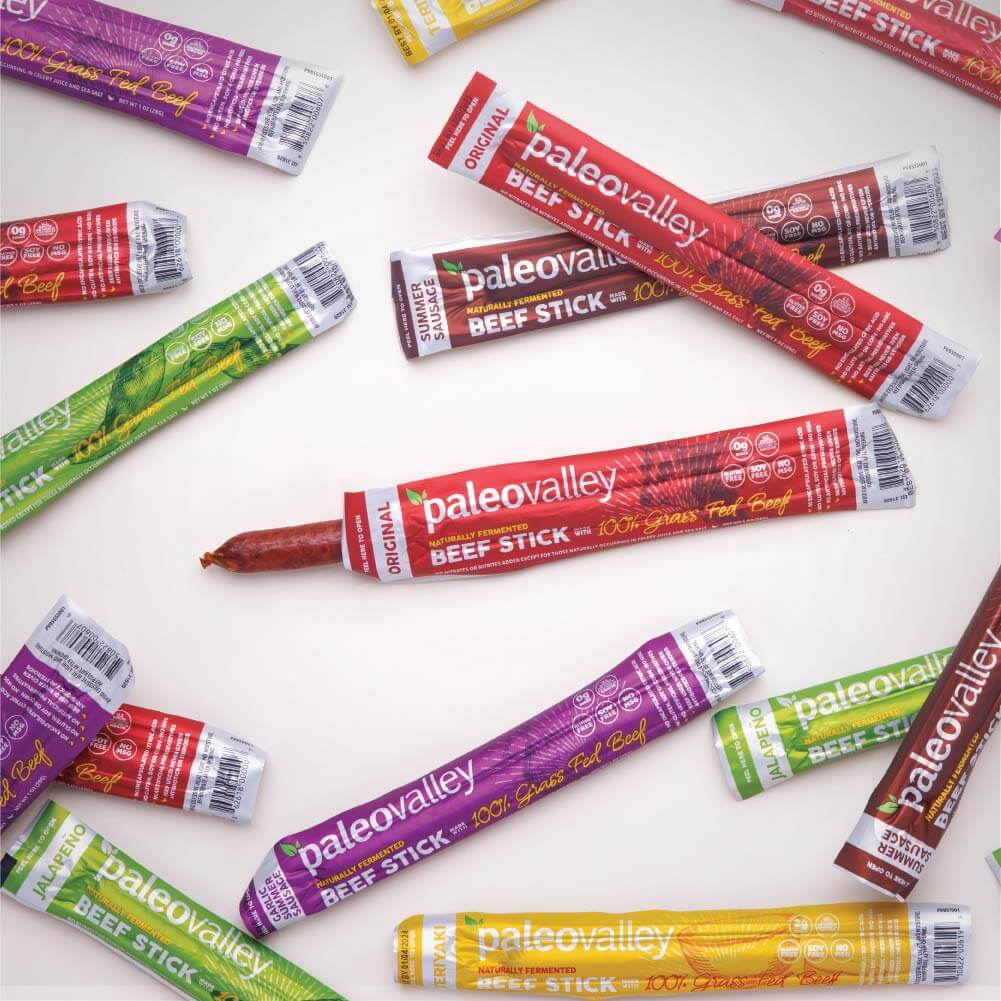 Assorted PaleoValley 100% grass-fed beef sticks in multiple flavors laid out on white background