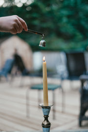 Person lighting a Busy Bees Hand Dipped 12 Inch Taper Candle outdoors in soft evening light.
