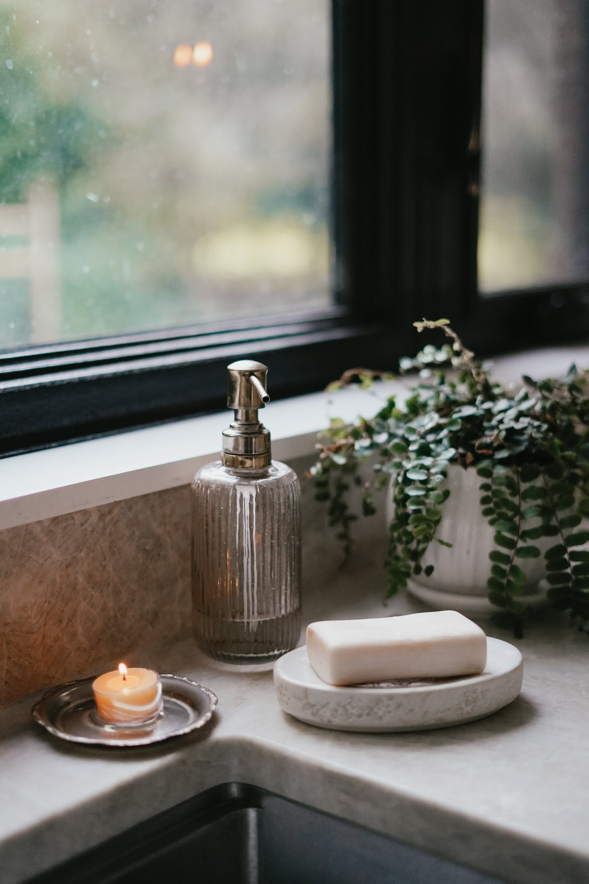 Busy Bees Bulk Loose Tea Light Candles styled beside a window with natural light, ceramic dishes, and soft floral accents.