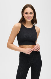 Full body studio portrait of a woman wearing the Elastique Athletics The Fierce Bra in black with matching leggings.